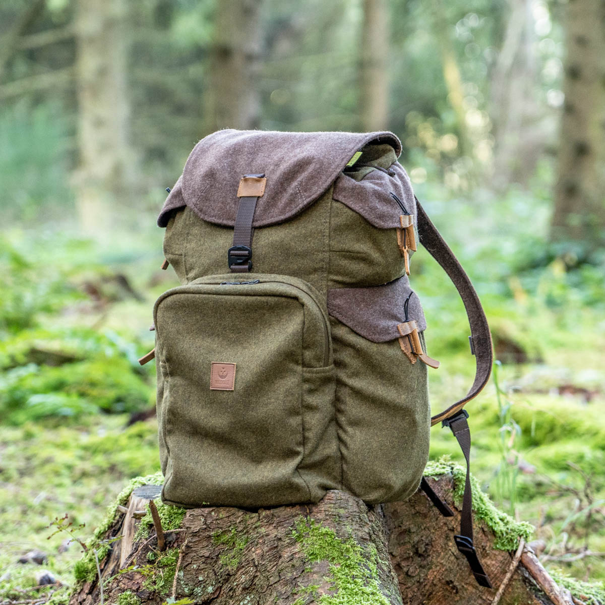 Grünbrauner Jagdrucksack auf Holzwurzel im Wald