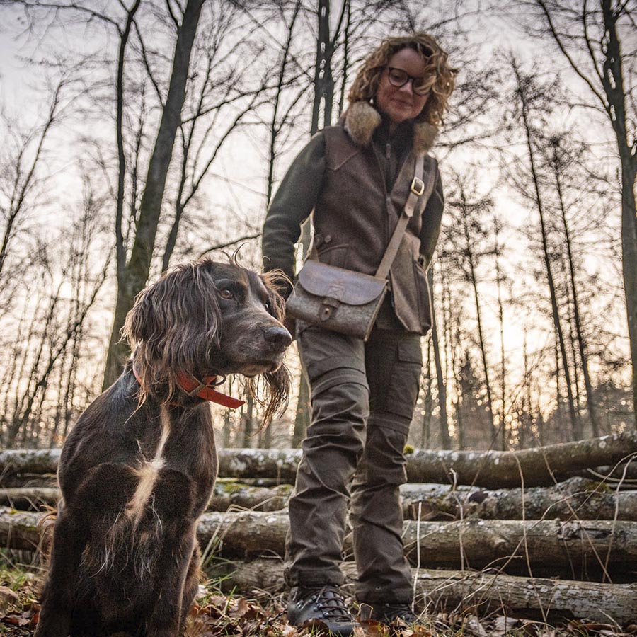 Jägerin mit Filztasche und Hund im Wald